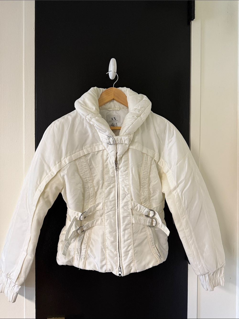Armani Exchange white puffer jacket with a high collar and buckle waist accents.